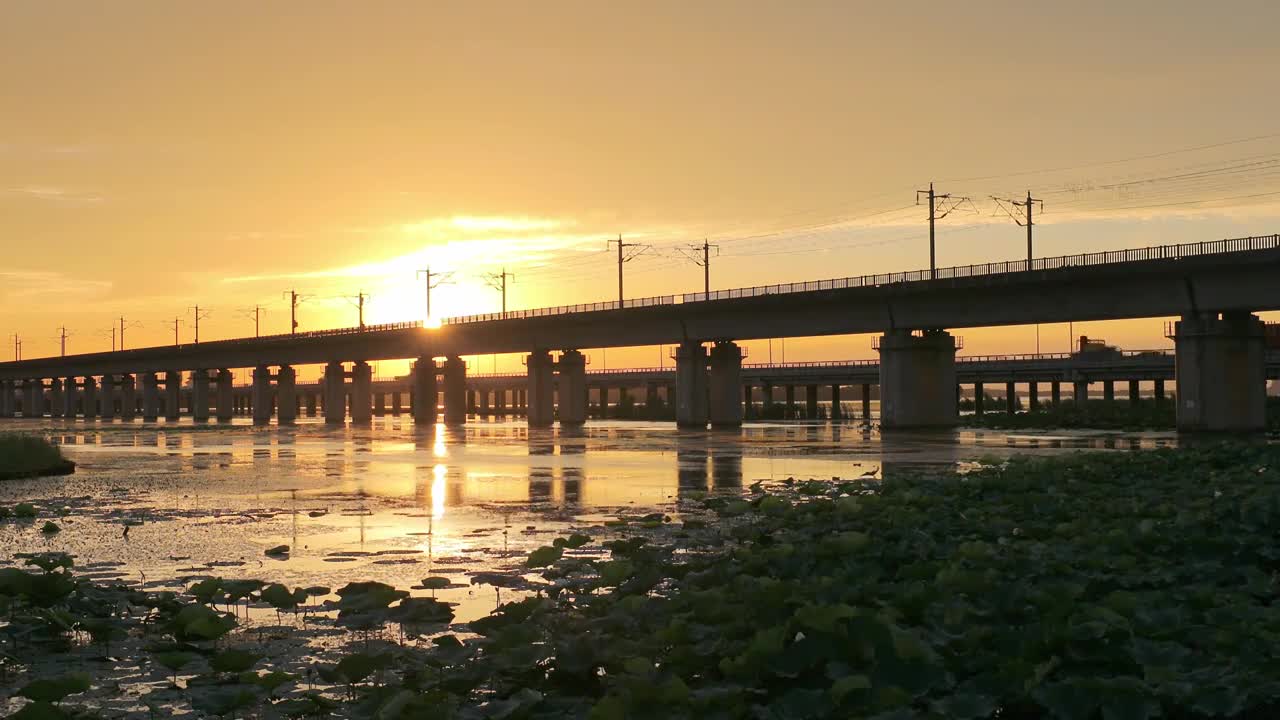 傍晚时分晚霞里的苏州阳澄湖上高铁与车流风景航拍视频下载