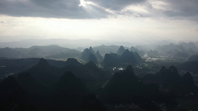 阳光透过乌云洒在群山之间的田野大地视频素材