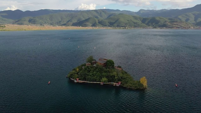 空中俯瞰泸沽湖王妃岛四周船只来来往往的景观视频素材