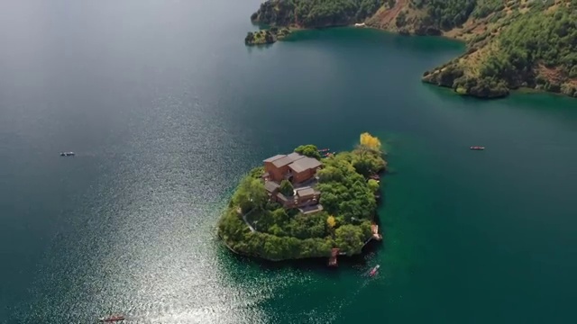 空中俯瞰泸沽湖王妃岛四周船只来来往往的景观视频素材