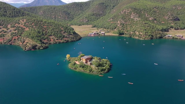 空中俯瞰泸沽湖王妃岛四周船只来来往往的景观视频素材