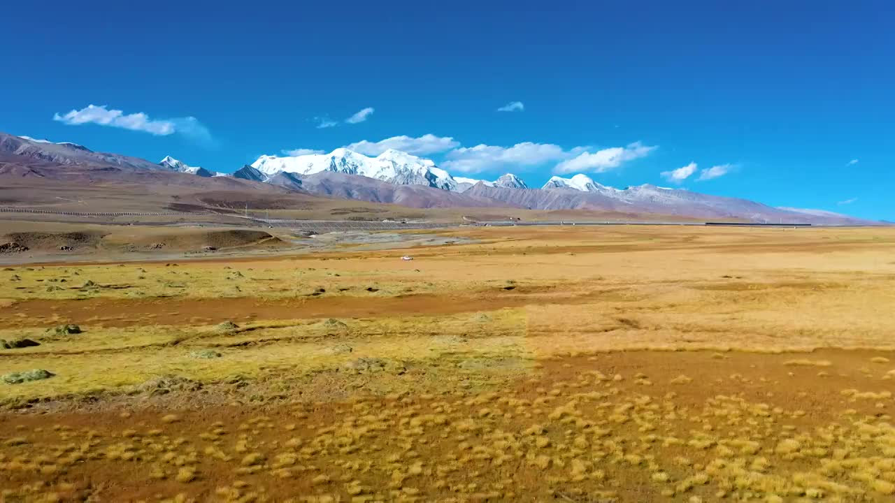 蓝天白云下的念青唐古拉山，青藏铁路火车飞驰，航拍视频素材