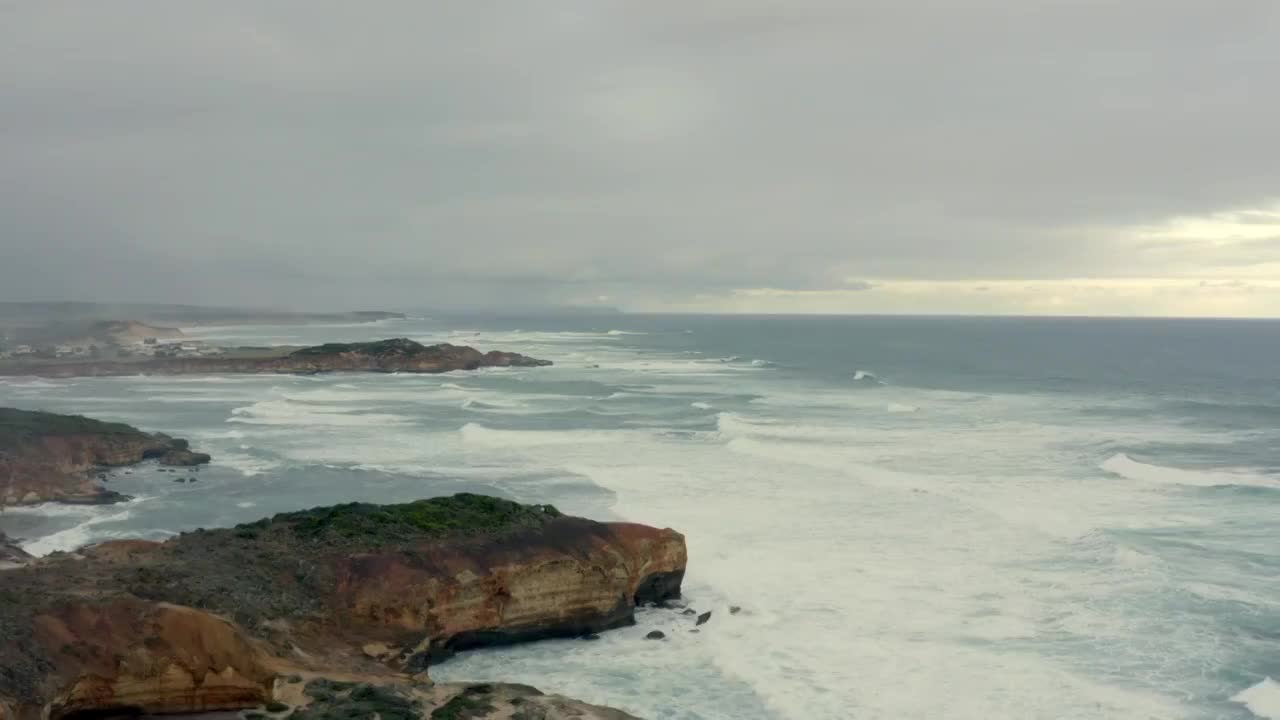 航拍阴天的海岸线 海浪不断拍打着沿岸 天空布满云 显得阴沉视频素材