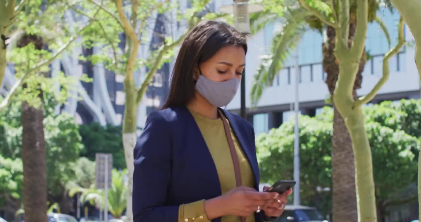 非裔美国妇女戴着口罩在街上用智能手机视频素材