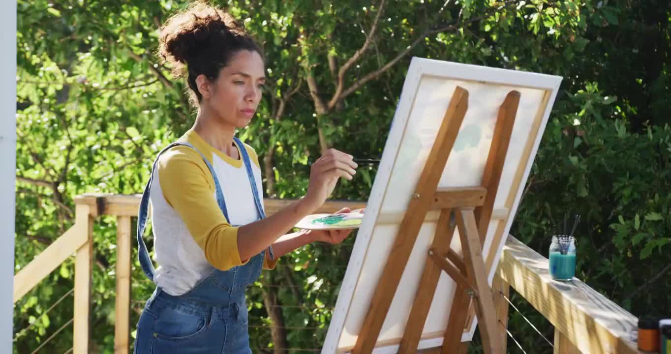 一名混血儿妇女在自家阳台的帆布上作画视频素材