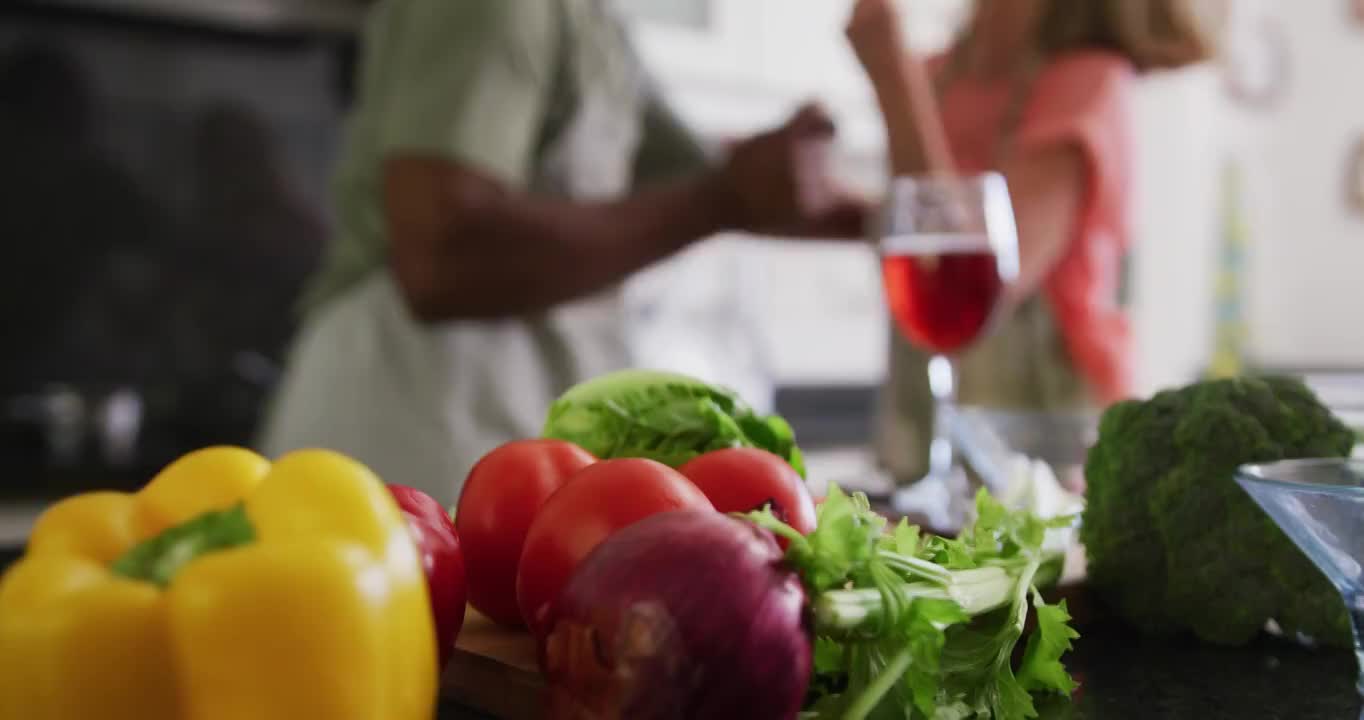 身穿围裙的各种老年夫妇在厨房准备食物时翩翩起舞视频素材