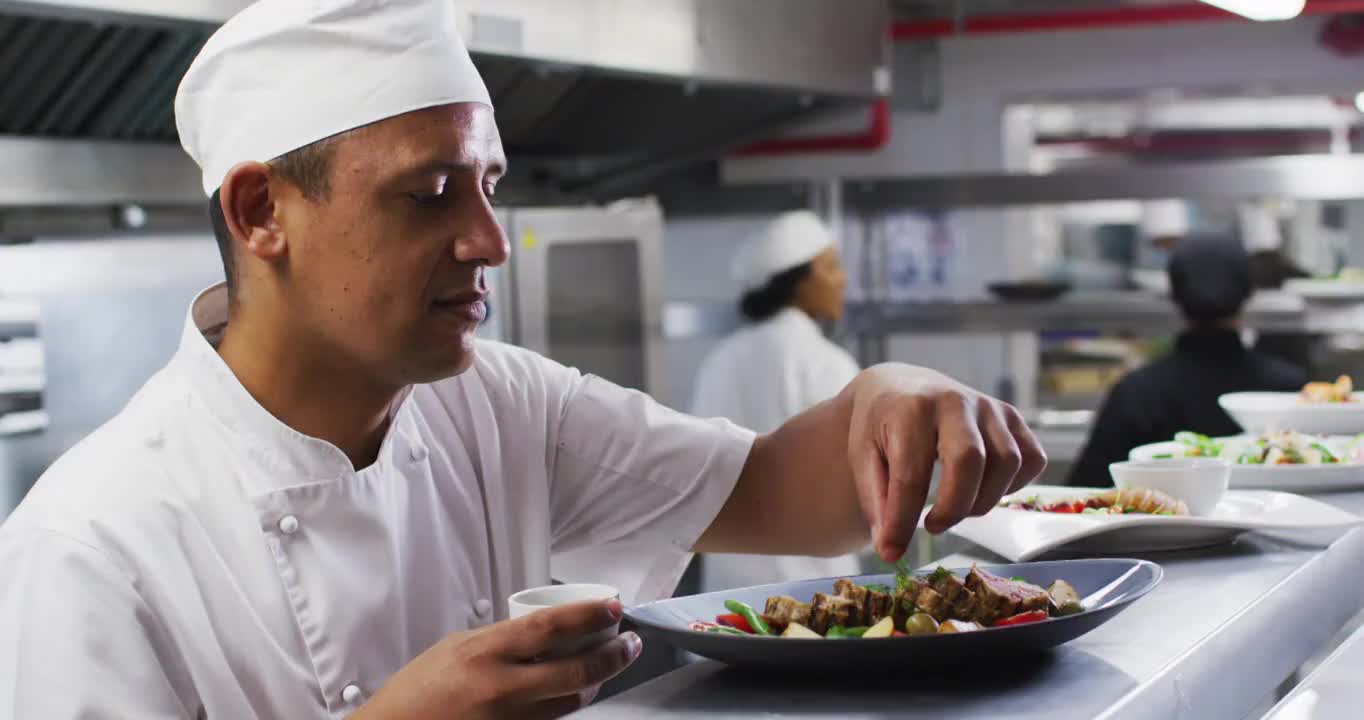 白种男厨师在餐厅厨房里微笑着装饰菜肴视频素材