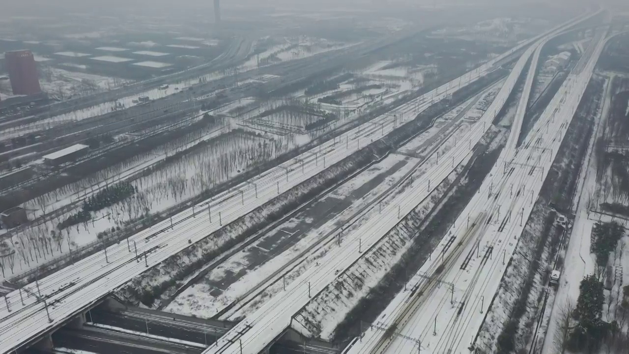 河南郑州高铁站郑州东站和谐号高铁进出站冬季雪景户外航拍视频素材