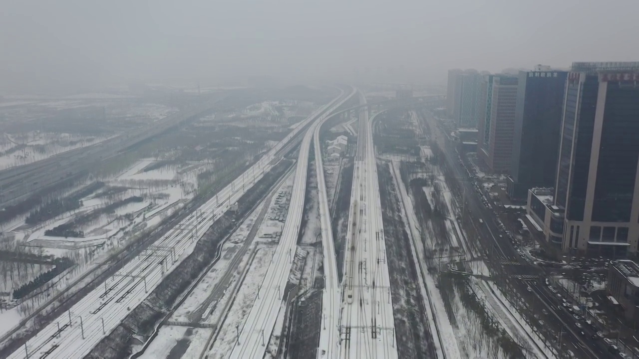 河南郑州高铁站郑州东站和谐号高铁进出站冬季雪景户外航拍视频素材