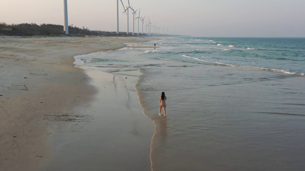 航拍海南文昌海岸沙滩风力发电机少女海滩行走视频素材