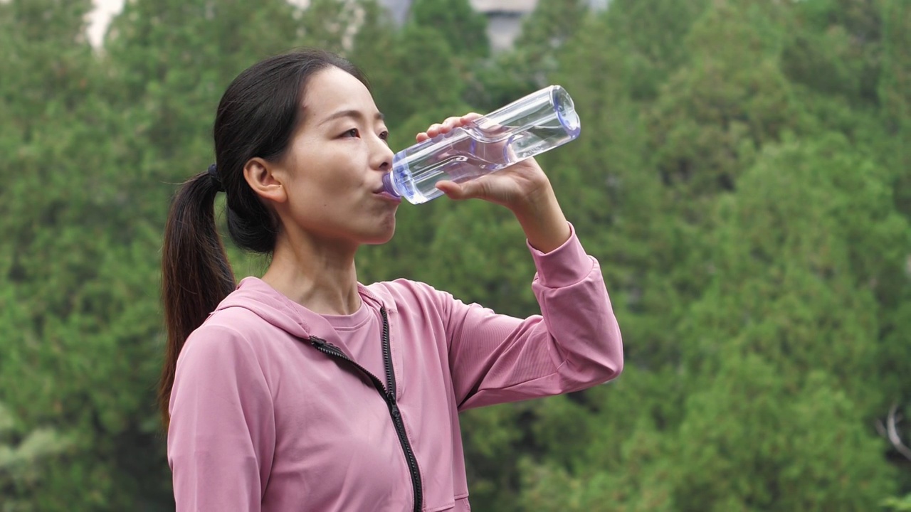 亚洲中国人女性在户外森林大自然喝水饮用水视频素材