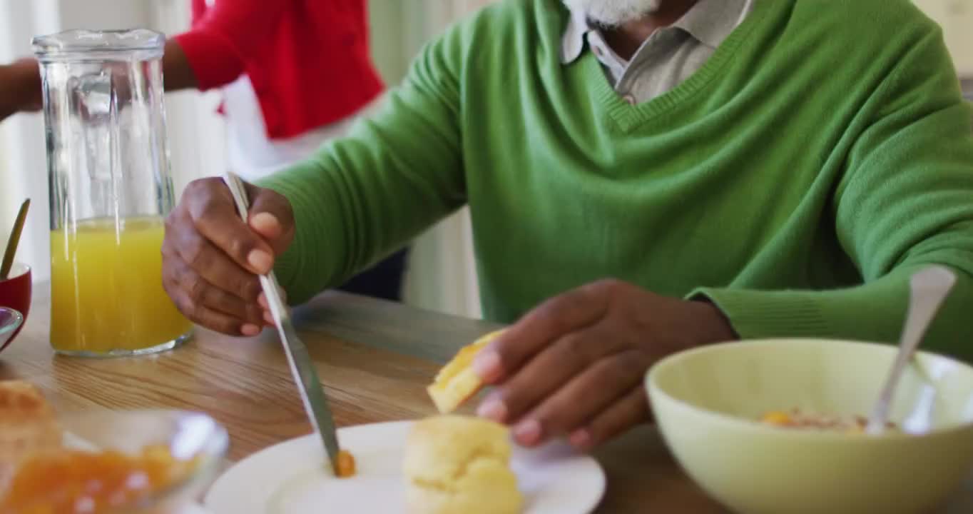 非裔美国老人在家里和家人吃早餐时涂果酱视频素材