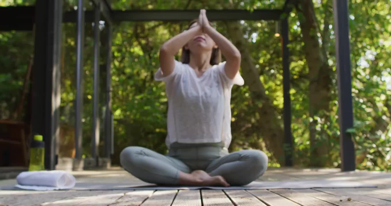 亚洲妇女冥想和坐在瑜伽垫在花园视频素材