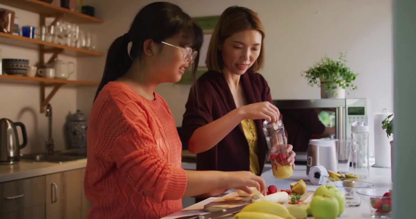 亚洲母亲和女儿在厨房准备健康饮料微笑视频素材