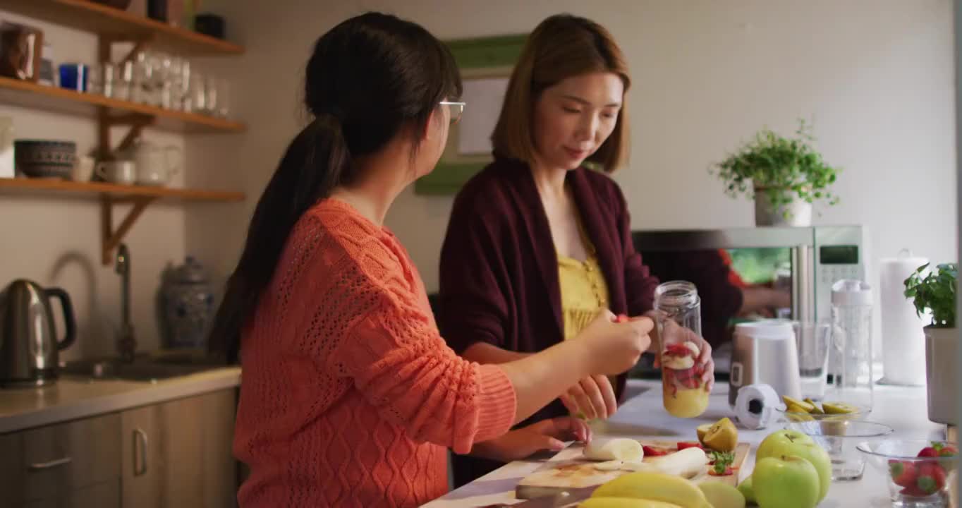 亚洲母亲和女儿在厨房准备健康饮料微笑视频素材