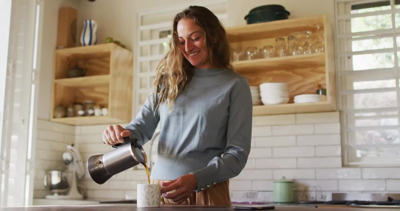 快乐的白人妇女站在村舍厨房倒咖啡从锅和微笑视频素材