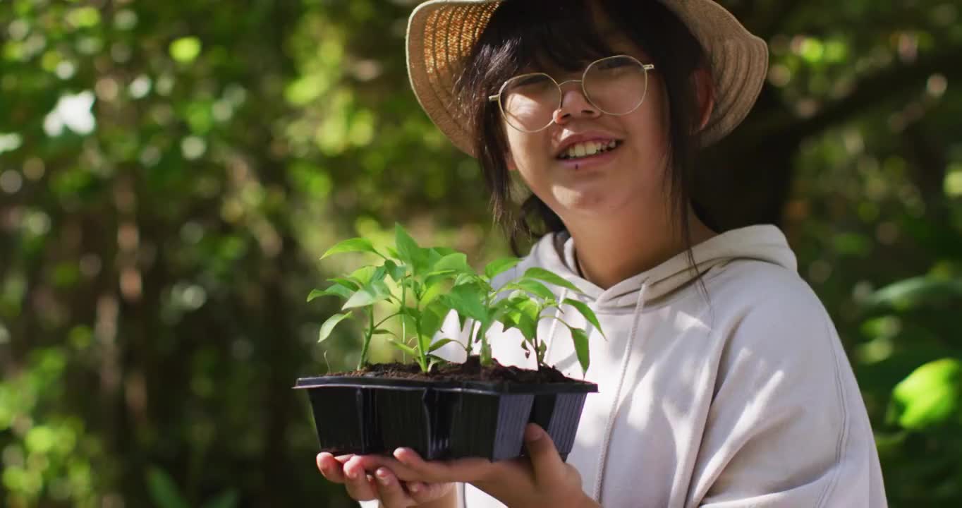 亚洲女孩在阳光明媚的日子里园艺和微笑的肖像视频素材