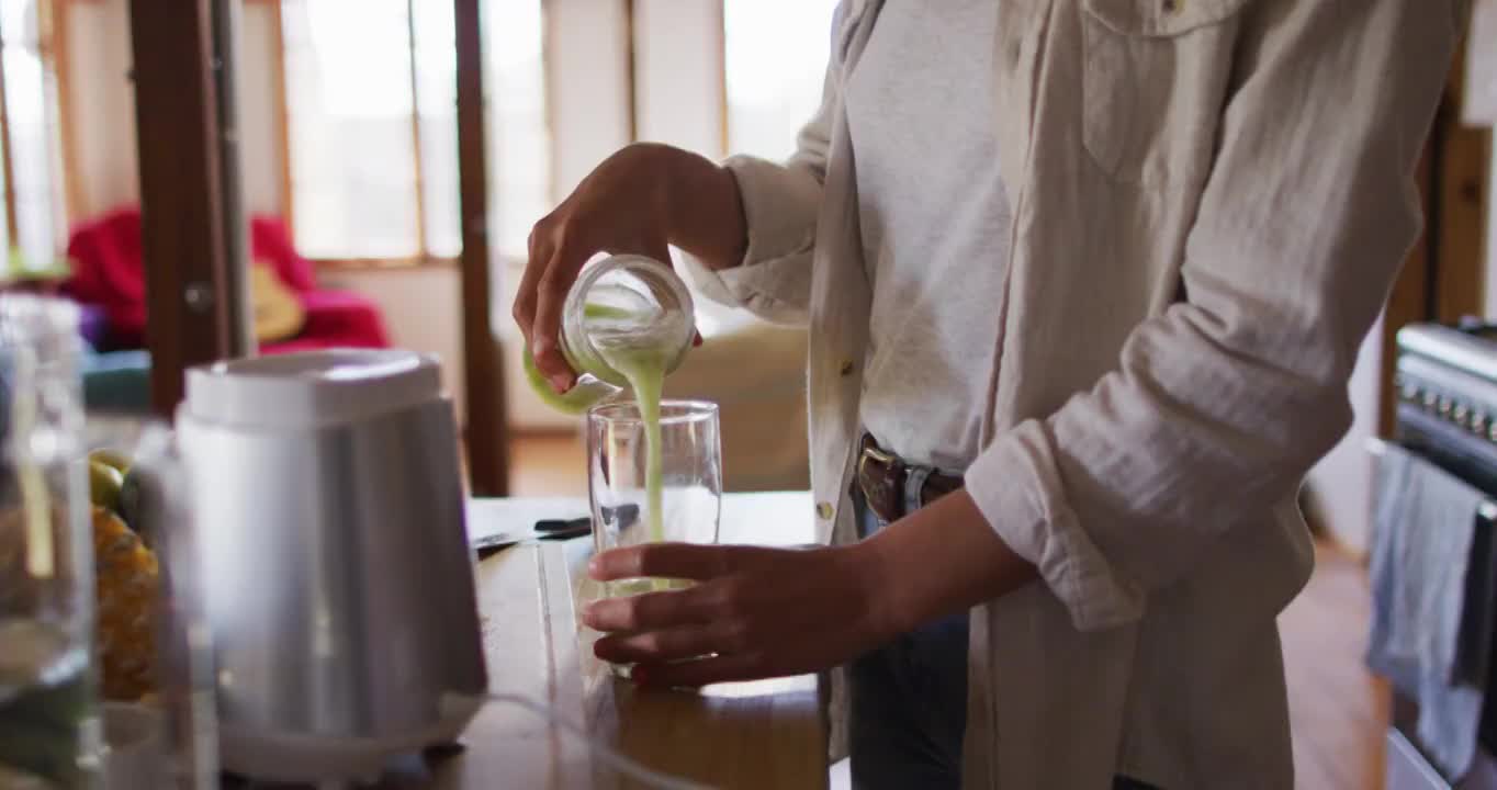 混血妇女正准备着健康饮料站在小屋厨房里微笑着视频素材