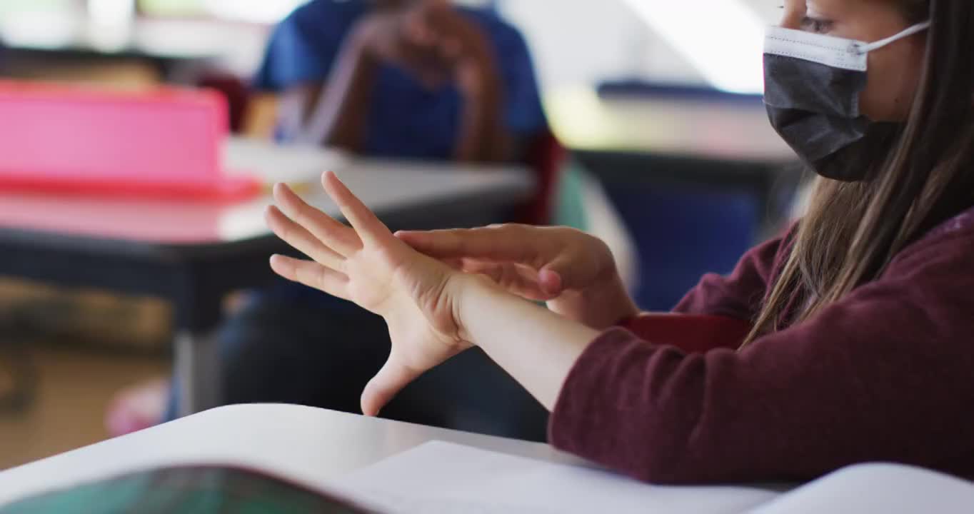 多名学童戴口罩坐在教室里消毒双手视频素材