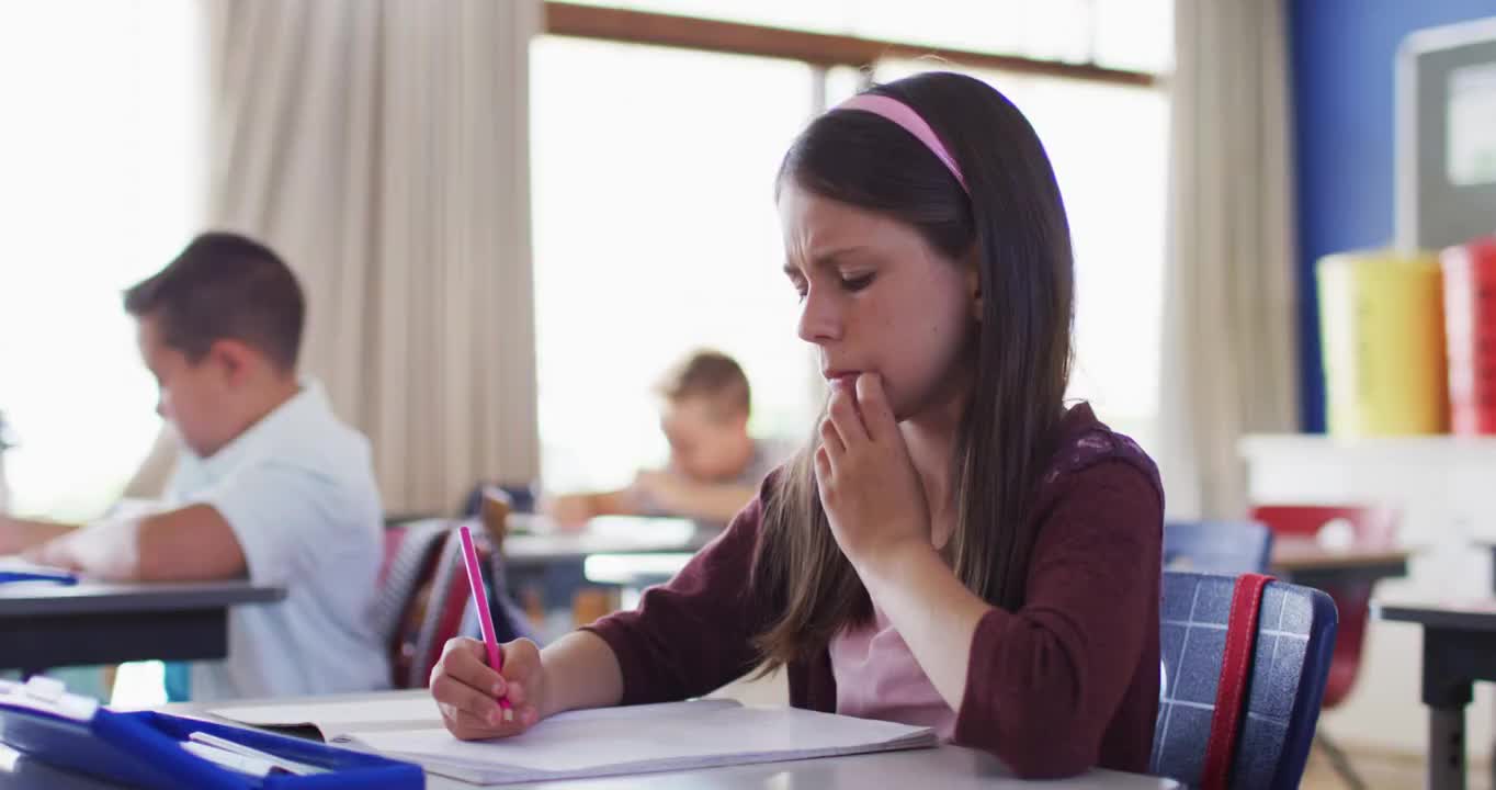 白人女学生坐在教室里做笔记的肖像视频素材