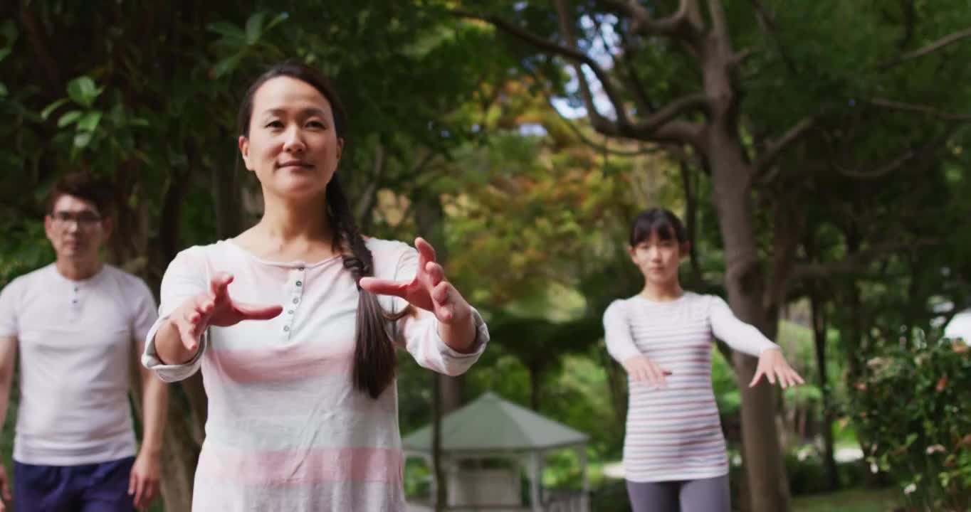 快乐的亚洲父母与儿子和女儿在花园里锻炼，一起练习太极视频素材