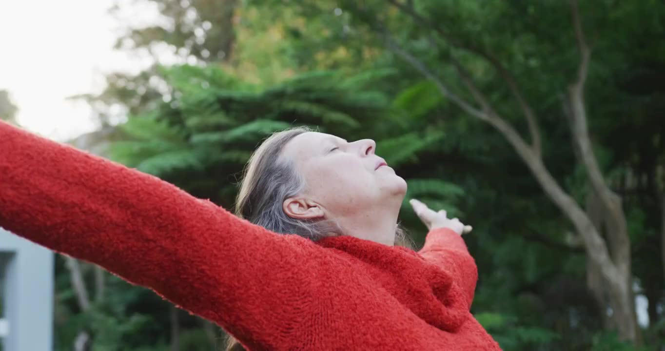 快乐的白人妇女站在花园伸展，放松与眼睛闭视频素材