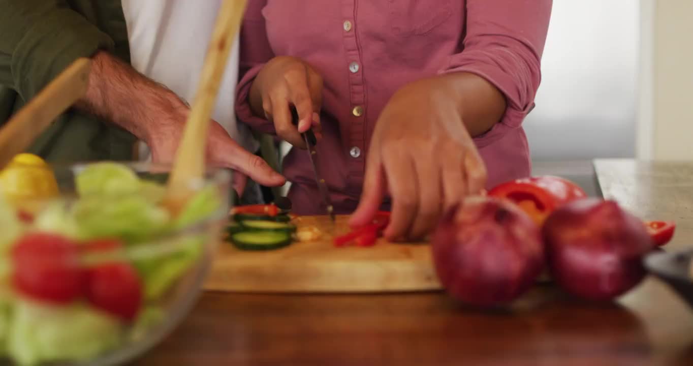 不同的夫妇在厨房一起准备食物，切蔬菜做沙拉视频素材