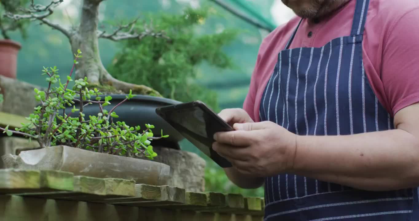 白人男性园丁中段在花园中心使用平板电脑视频素材