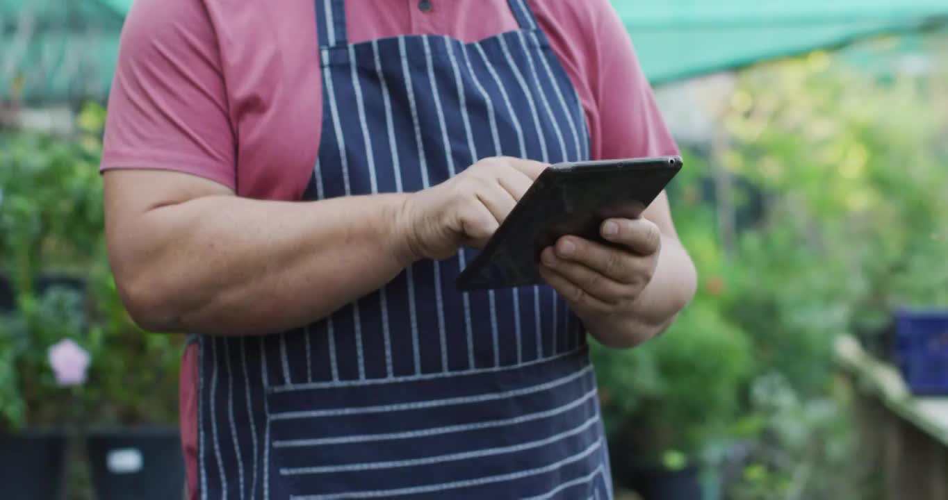 白人男性园丁中段在花园中心使用平板电脑视频素材