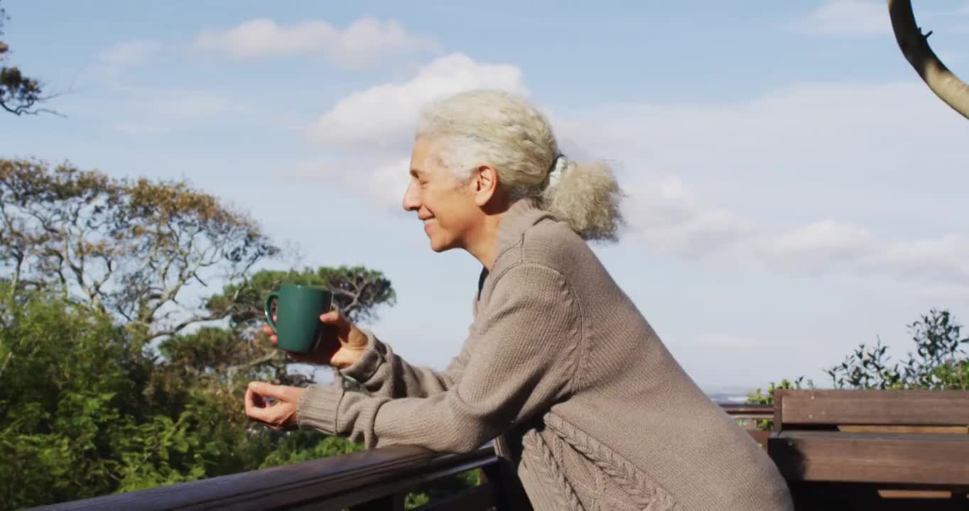 高级混血儿妇女在阳台上拿着杯子喝酒的肖像视频素材