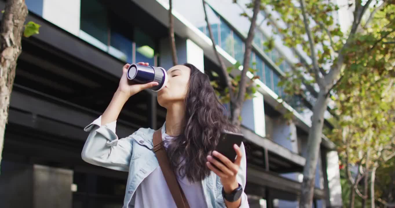 亚洲妇女走路用智能手机和喝外卖咖啡视频素材