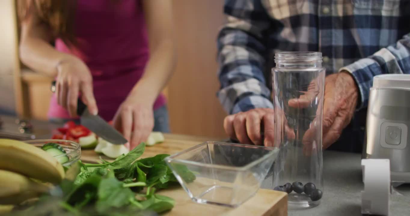 白人父亲和十几岁的女儿准备健康饮料和切水果在厨房视频素材