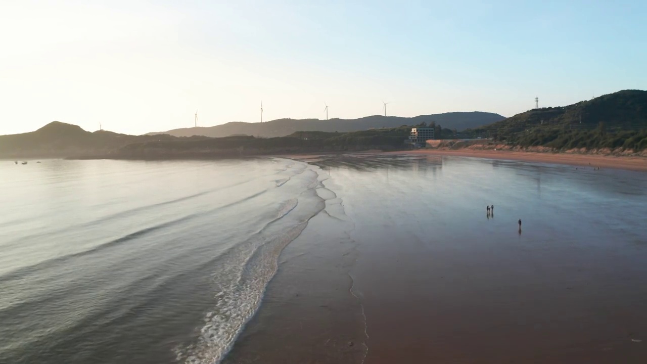 航拍海边风力发电场边的正在涨潮的海滩视频素材