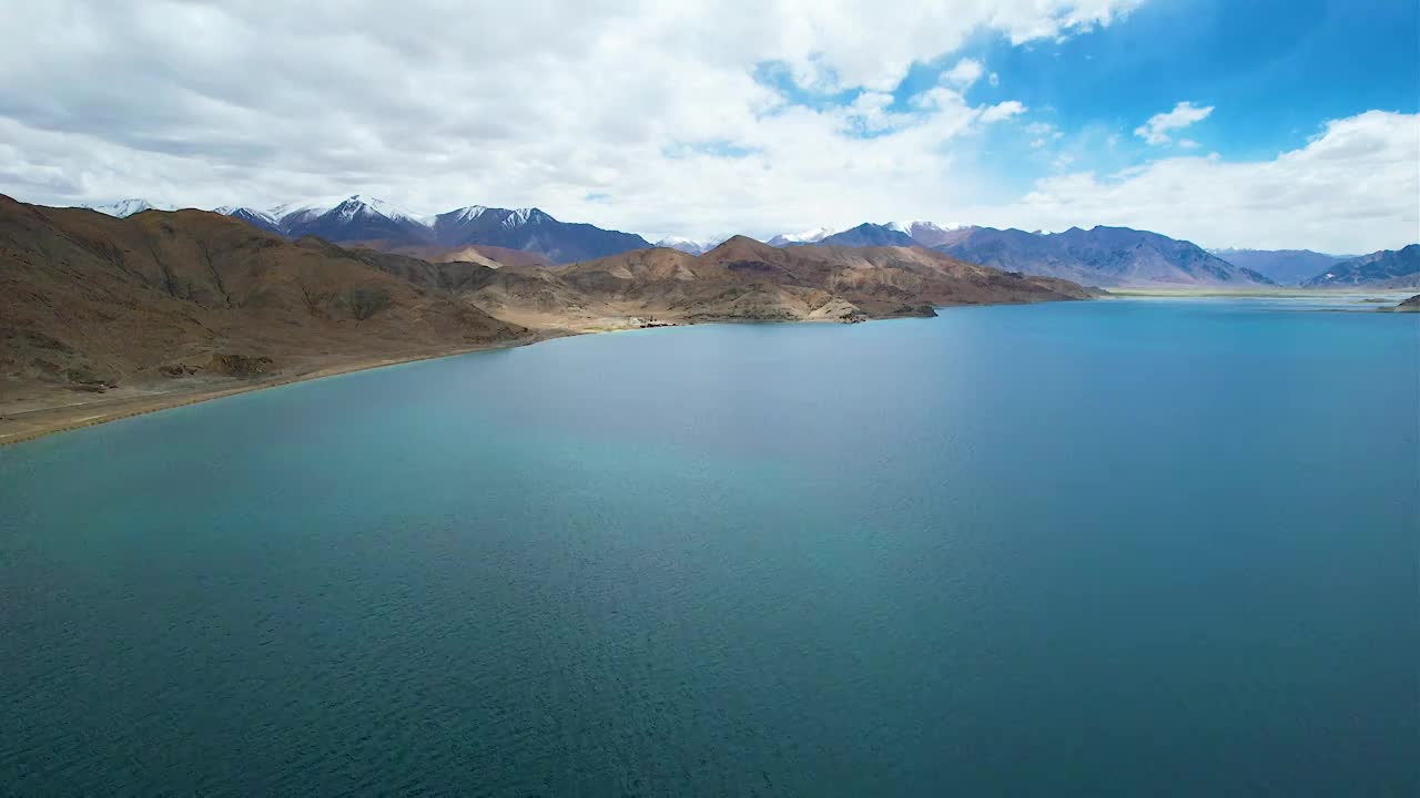 西藏阿里班公湖，六月晴朗的天气，航拍蓝天白云下，湖水湛蓝，雪山环抱，新藏公路从湖边经过。视频素材