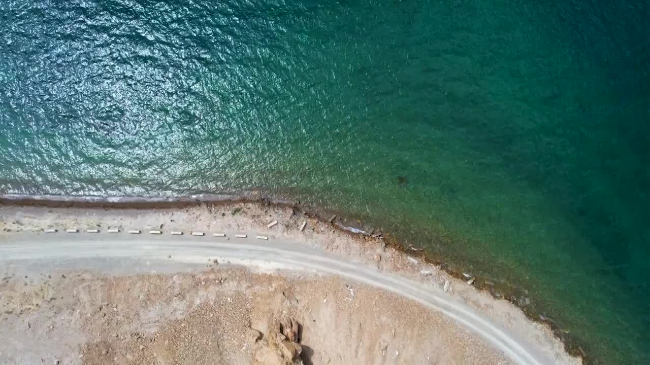 西藏阿里班公湖，六月晴朗的天气，航拍蓝天白云下，湖水湛蓝，雪山环抱，新藏公路从湖边经过。视频素材