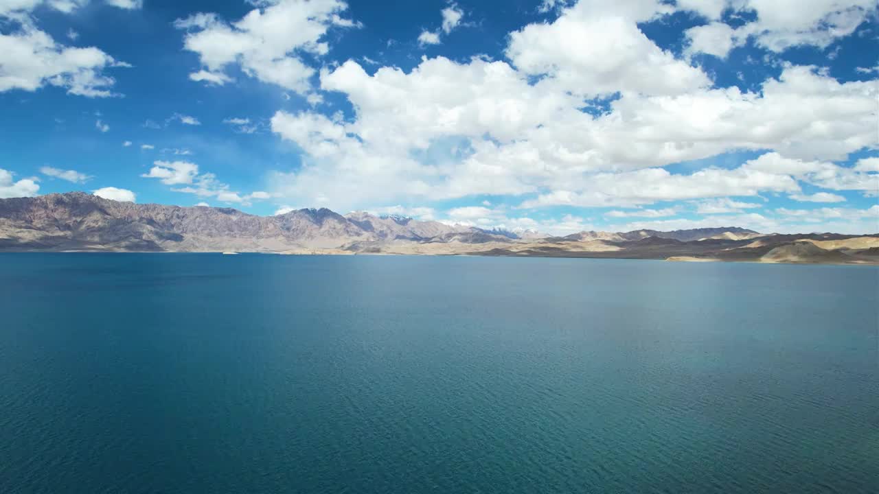 西藏阿里班公湖，六月晴朗的天气，航拍蓝天白云下，湖水湛蓝，雪山环抱，新藏公路从湖边经过。视频素材