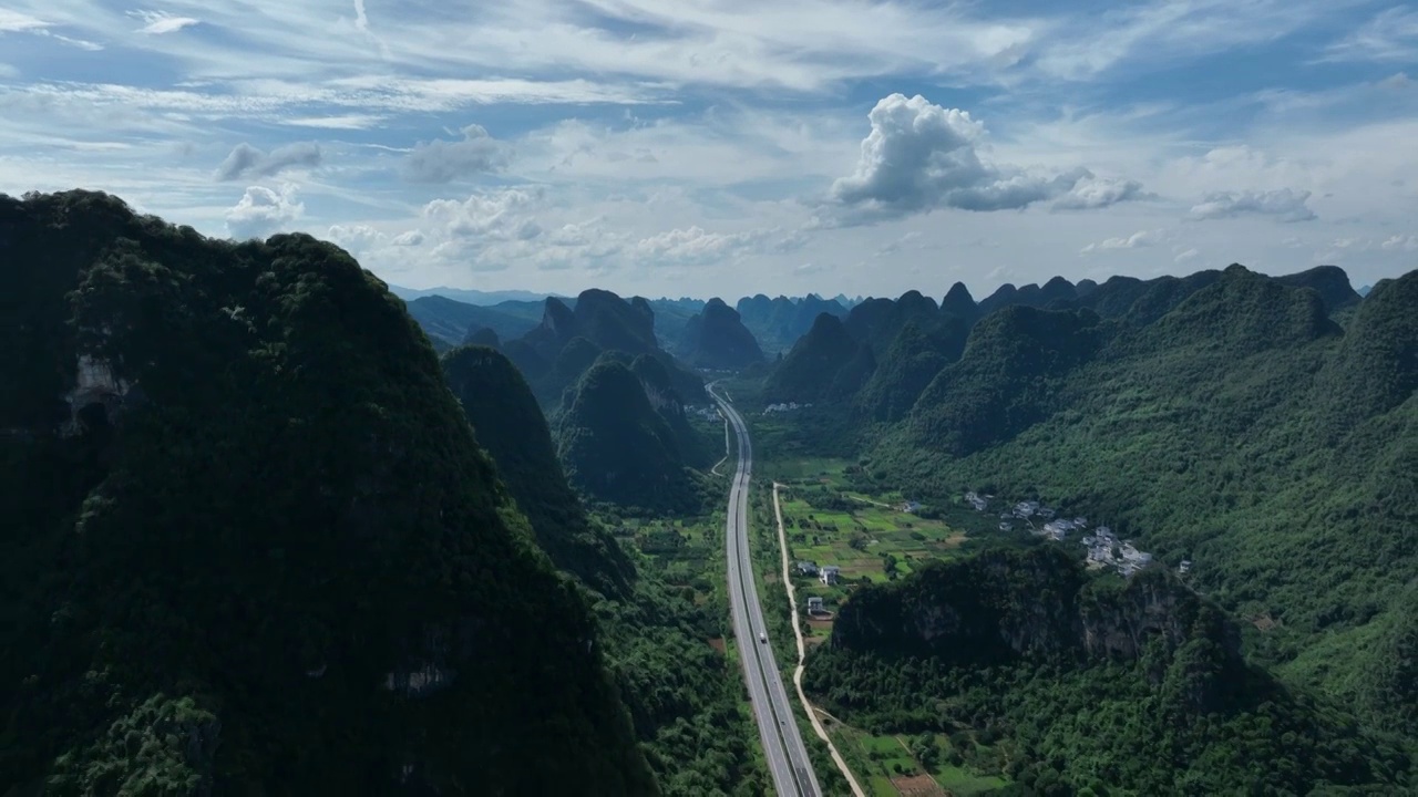 蓝天白云下喀斯特地貌峰林中穿行的高速公路视频素材