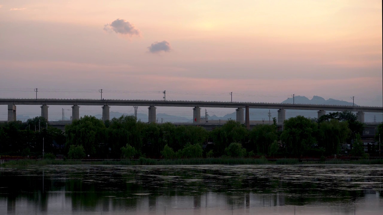 夕阳中行驶在晓月湖高架桥上的高速列车视频素材