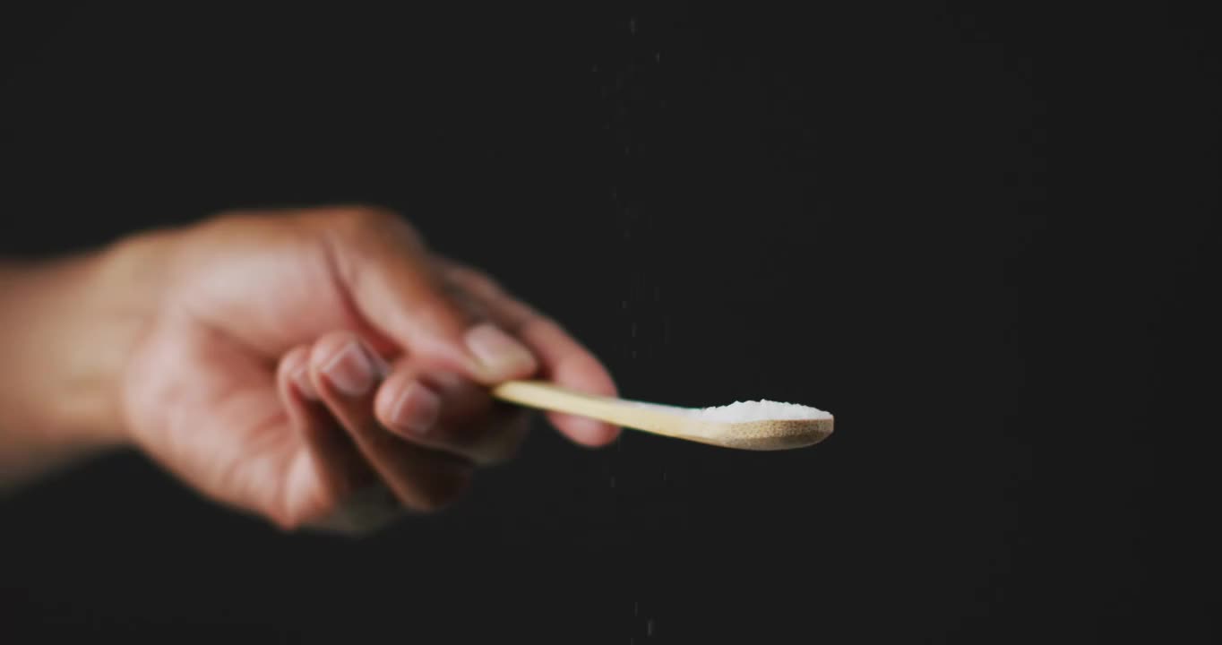 黑色背景下厨师向餐桌撒盐的视频视频素材