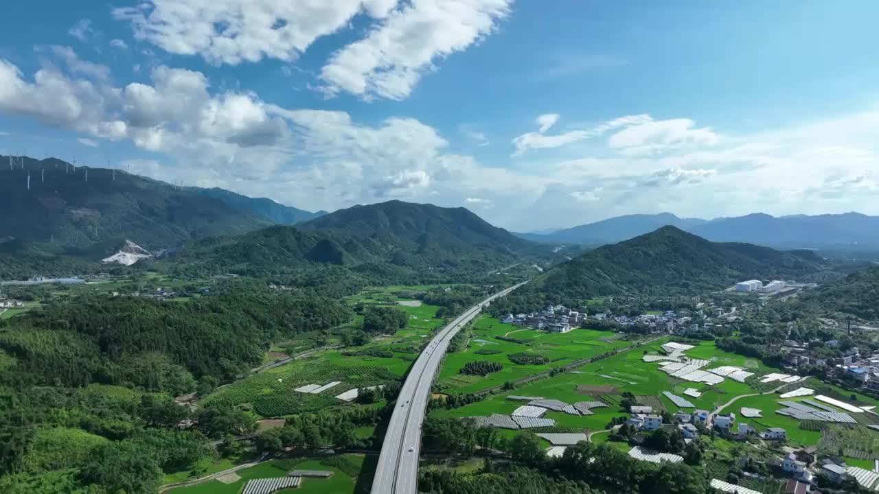 蓝天白云阳光下穿过山间田园的高速公路视频素材