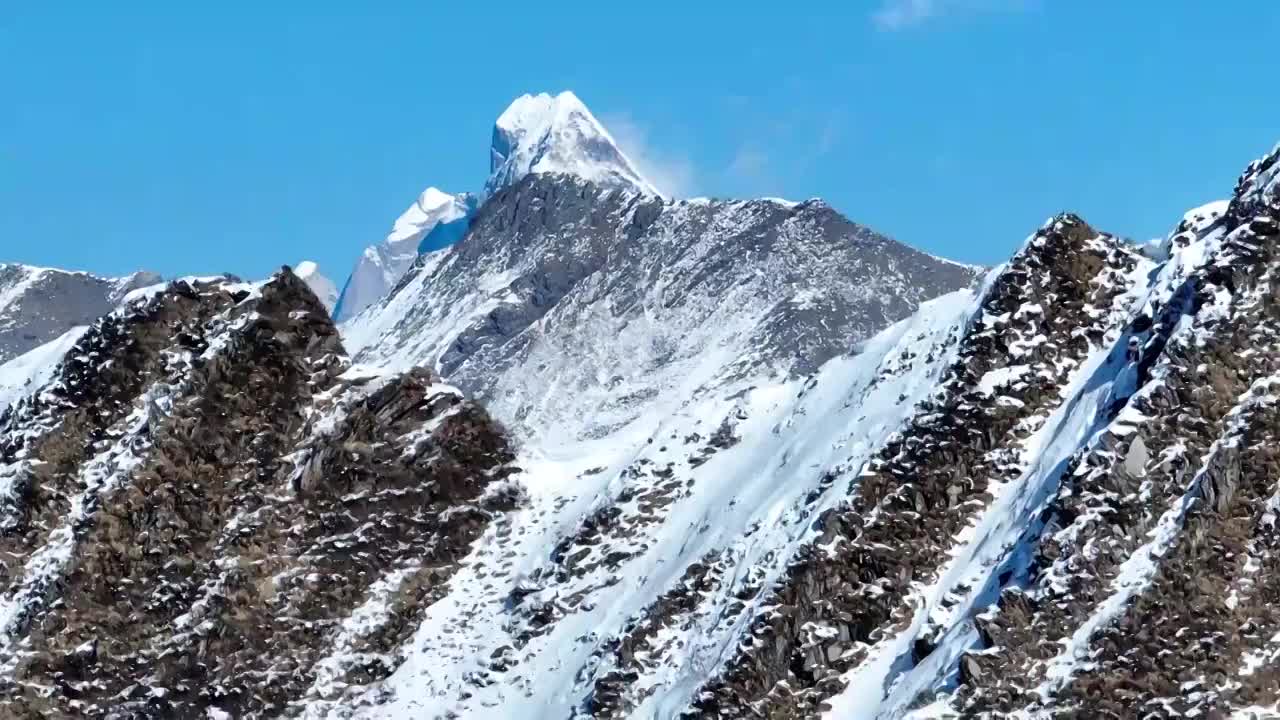 透过夹金山山脊航拍蓝天下的四姑娘山幺妹峰视频素材