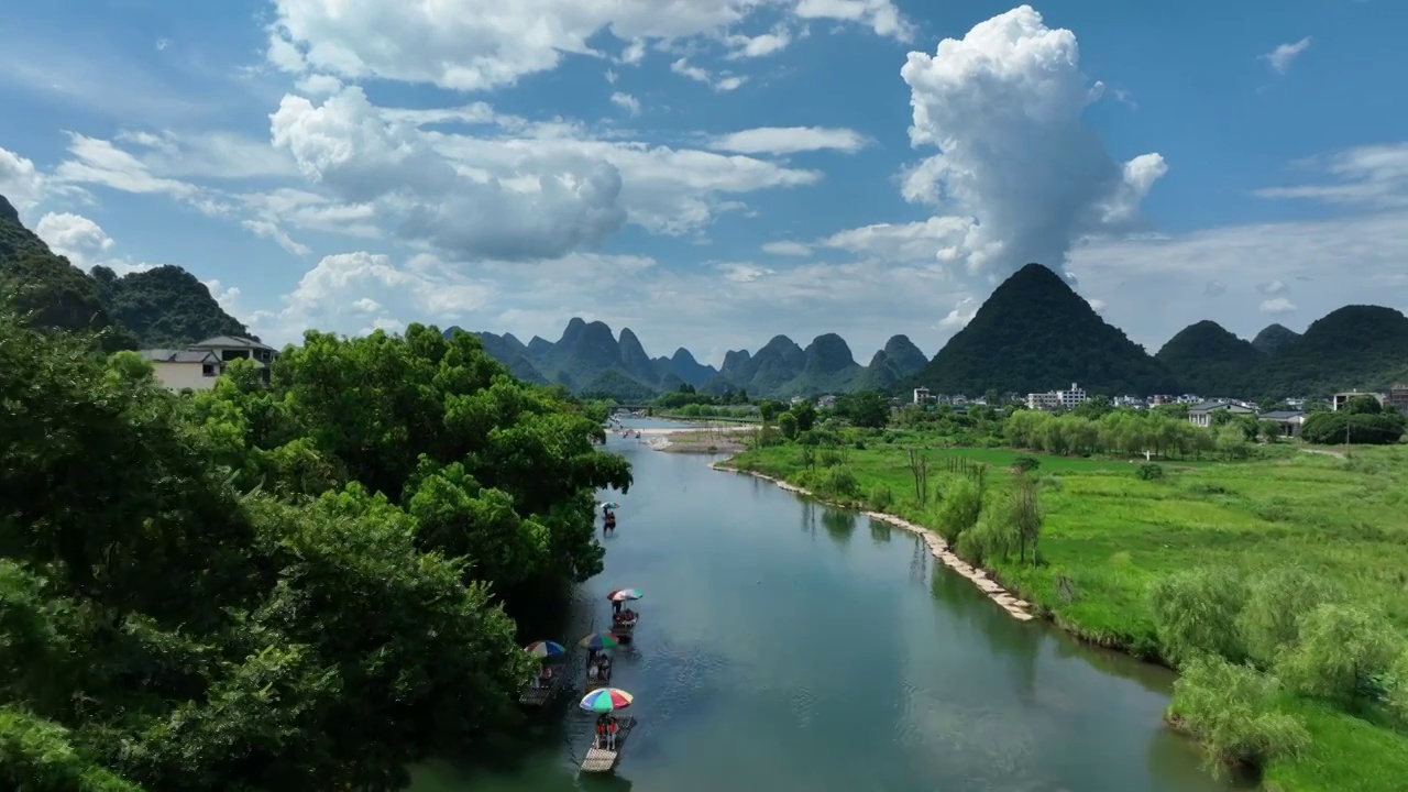 蓝天白云下阳朔遇龙河上漂流的竹筏和两岸的田园风光视频素材