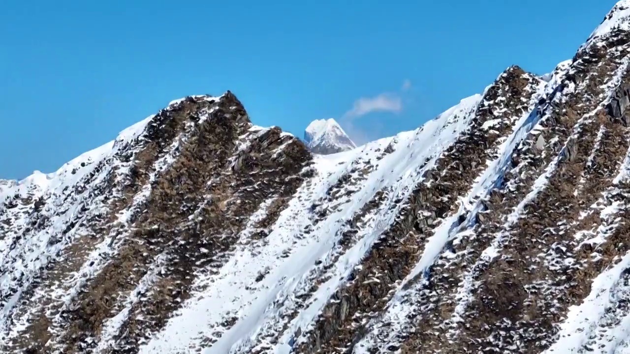 透过雪山夹金山山脊航拍四姑娘山幺妹峰风景视频素材