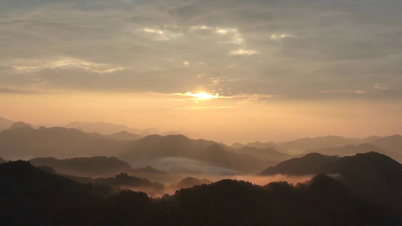 晨光中一轮红日从远山的天边喷薄而出，山谷中的云海蔓延山峦后，融入到了绯红的天际。视频下载