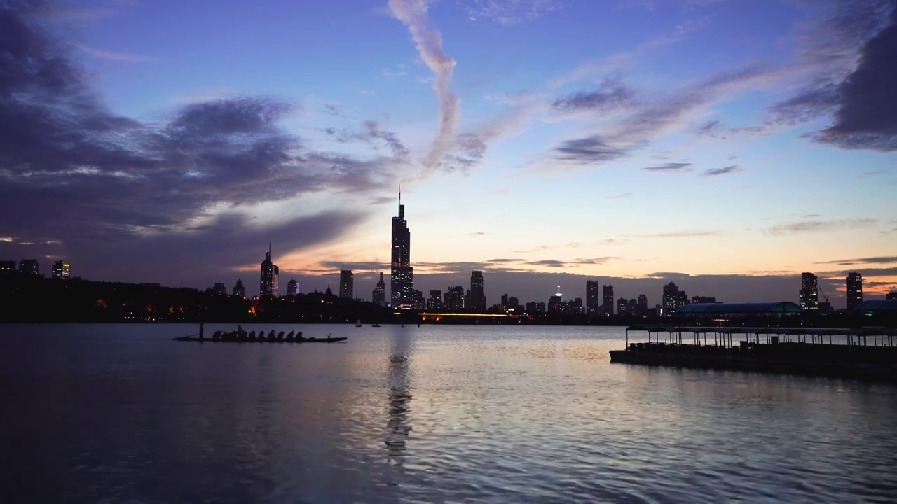 黄昏傍晚时分南京玄武湖上的龙舟训练和城市夜景风光视频素材