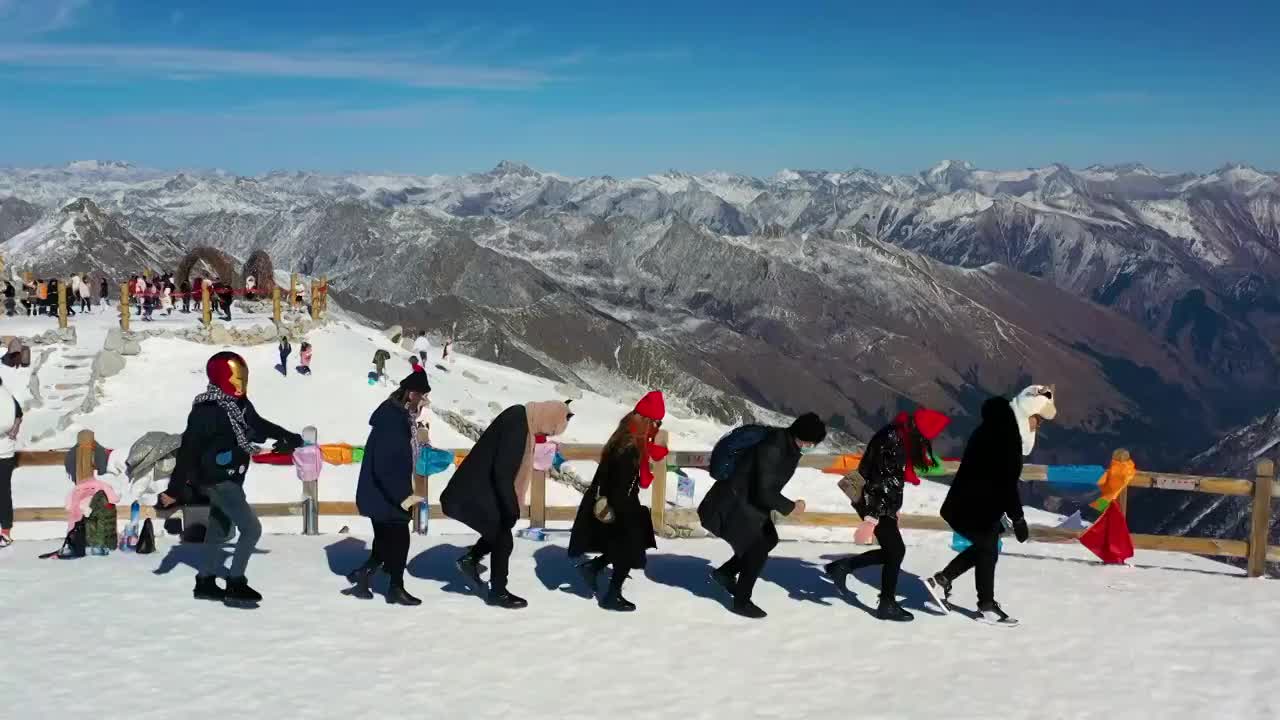 航拍游客在达古冰川山顶雪山跳舞景象视频素材