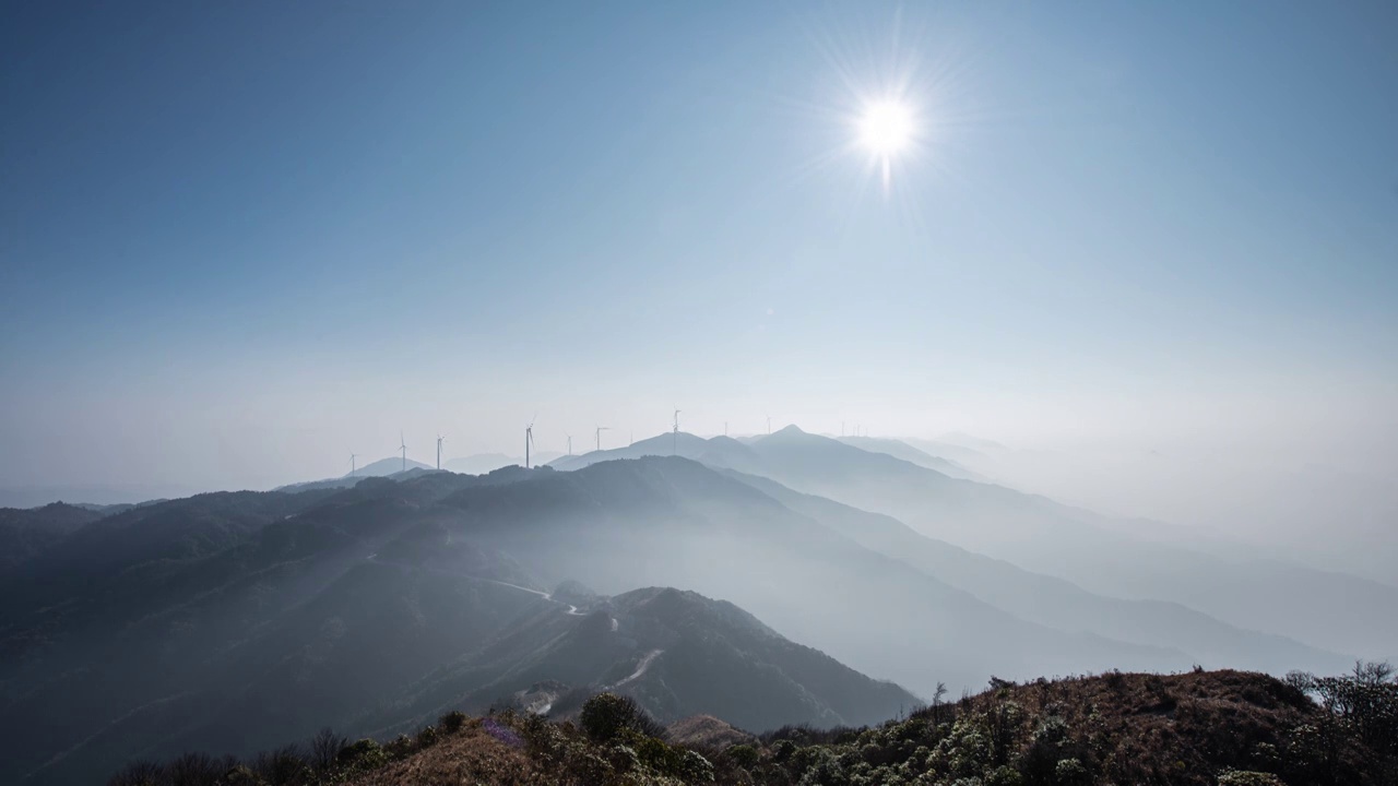 日落时分高海拔山谷中的雾和山顶的风力发电风车视频素材