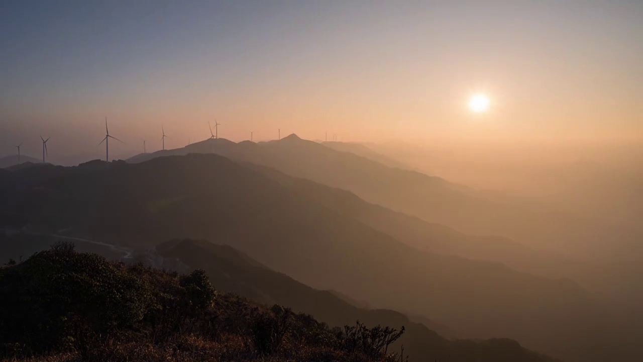 夕阳下高山上的风力发电风车和山谷中的云雾视频素材