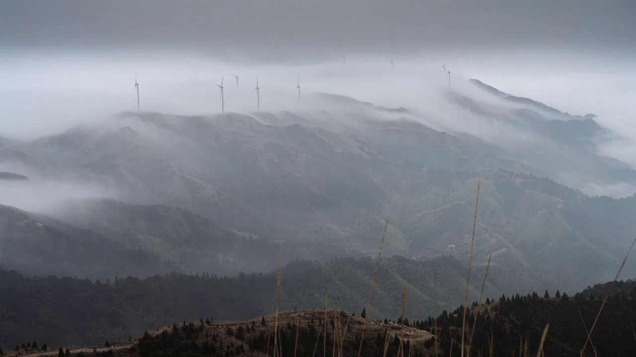 清晨高海拔山顶上的风力发电风车和山谷中涌动的云雾视频素材