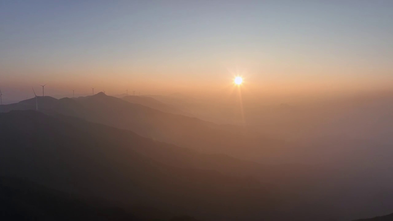 夕阳暮色中高海拔山顶的风力发电风车和山谷中涌动的云雾视频素材